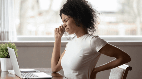 Woman sitting at her work desk with back pain
