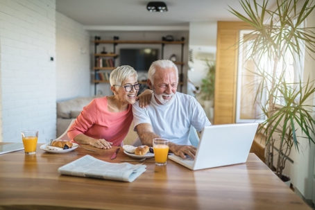 older couple smiling while looking at laptop