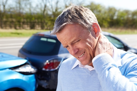 older man grasping neck in pain after a car accident
