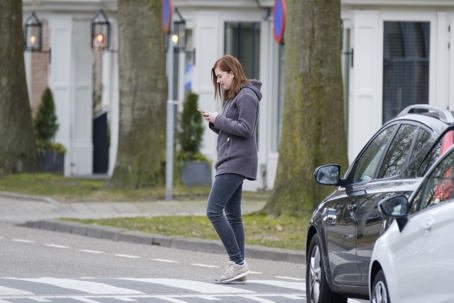 young woman walks on the crosswalk and checks her smartphone for messages and does not pay any attention to traffic