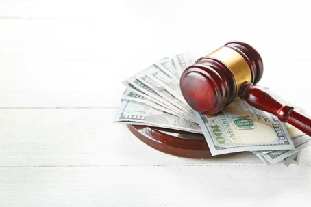 gavel sitting on top of stack of cash on white background