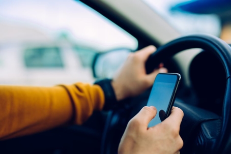 up-close view of someone using their phone while driving